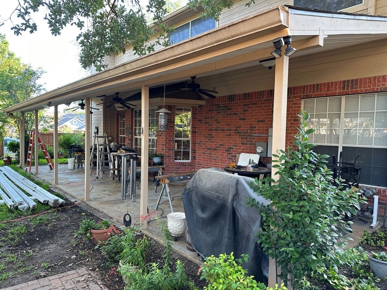 A covered porch is being built on the side of a brick house.