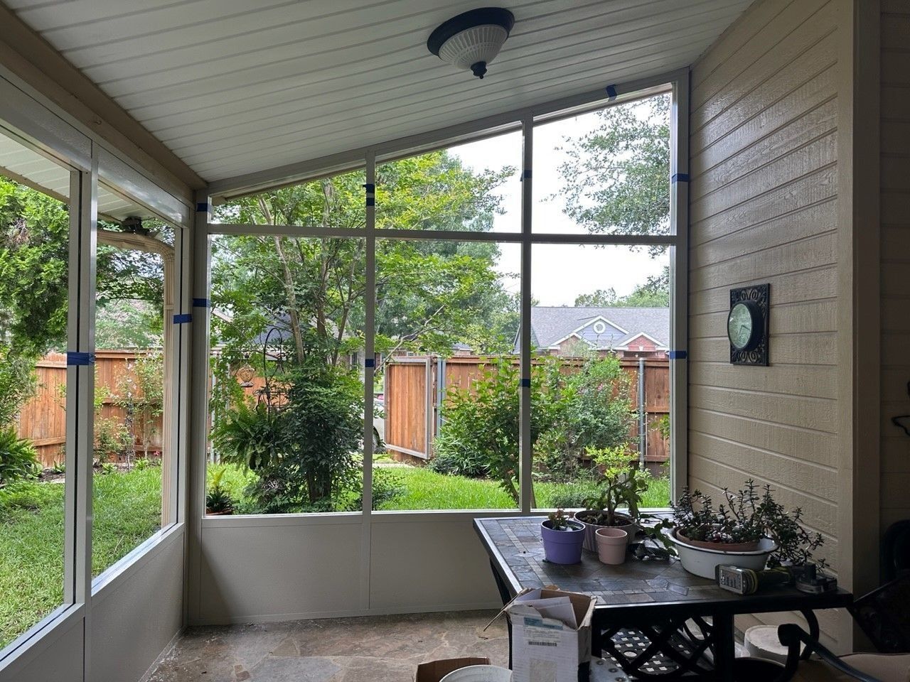 A screened in porch with a table and potted plants