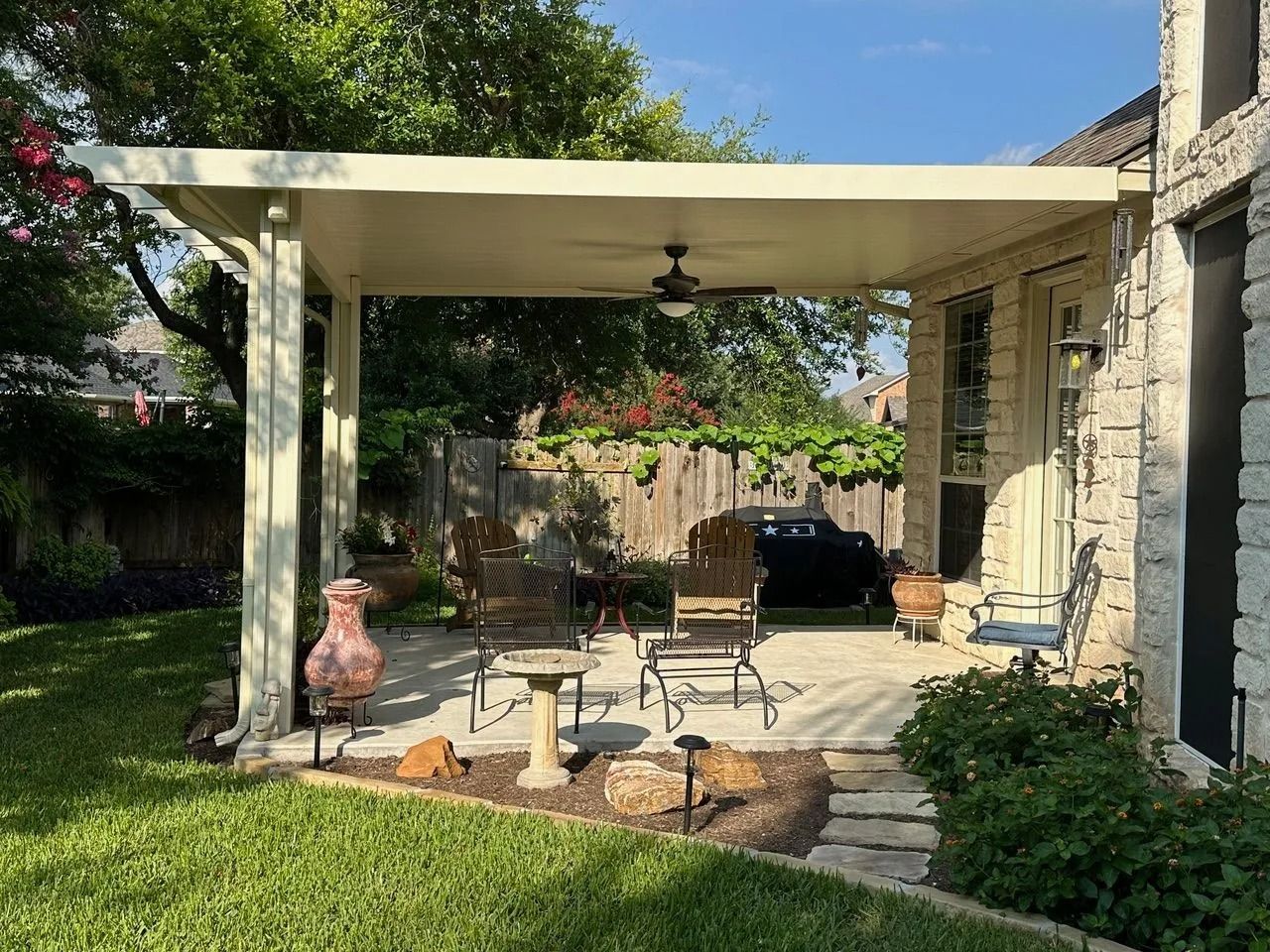 There is a patio with a ceiling fan in the backyard of a house.