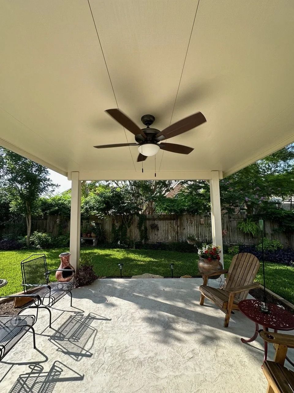 A man is sitting under a ceiling fan on a patio.