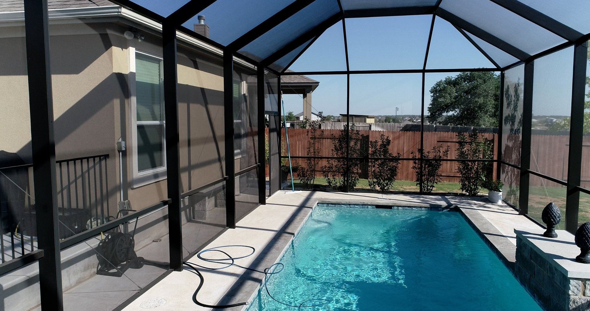 A screened in swimming pool with a house in the background