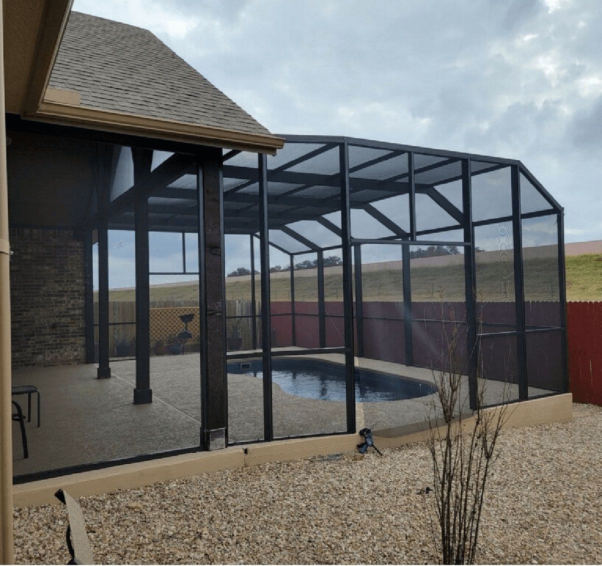 A screened in area with a pool in the background