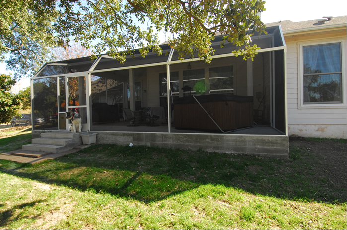 A house with a screened in porch and a hot tub