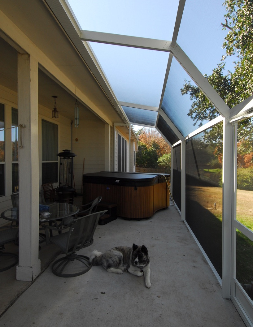 A dog laying on a patio next to a hot tub