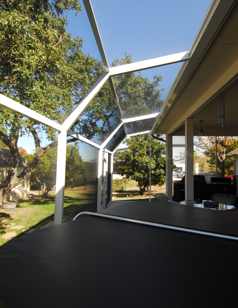 A patio with a clear roof and trees in the background
