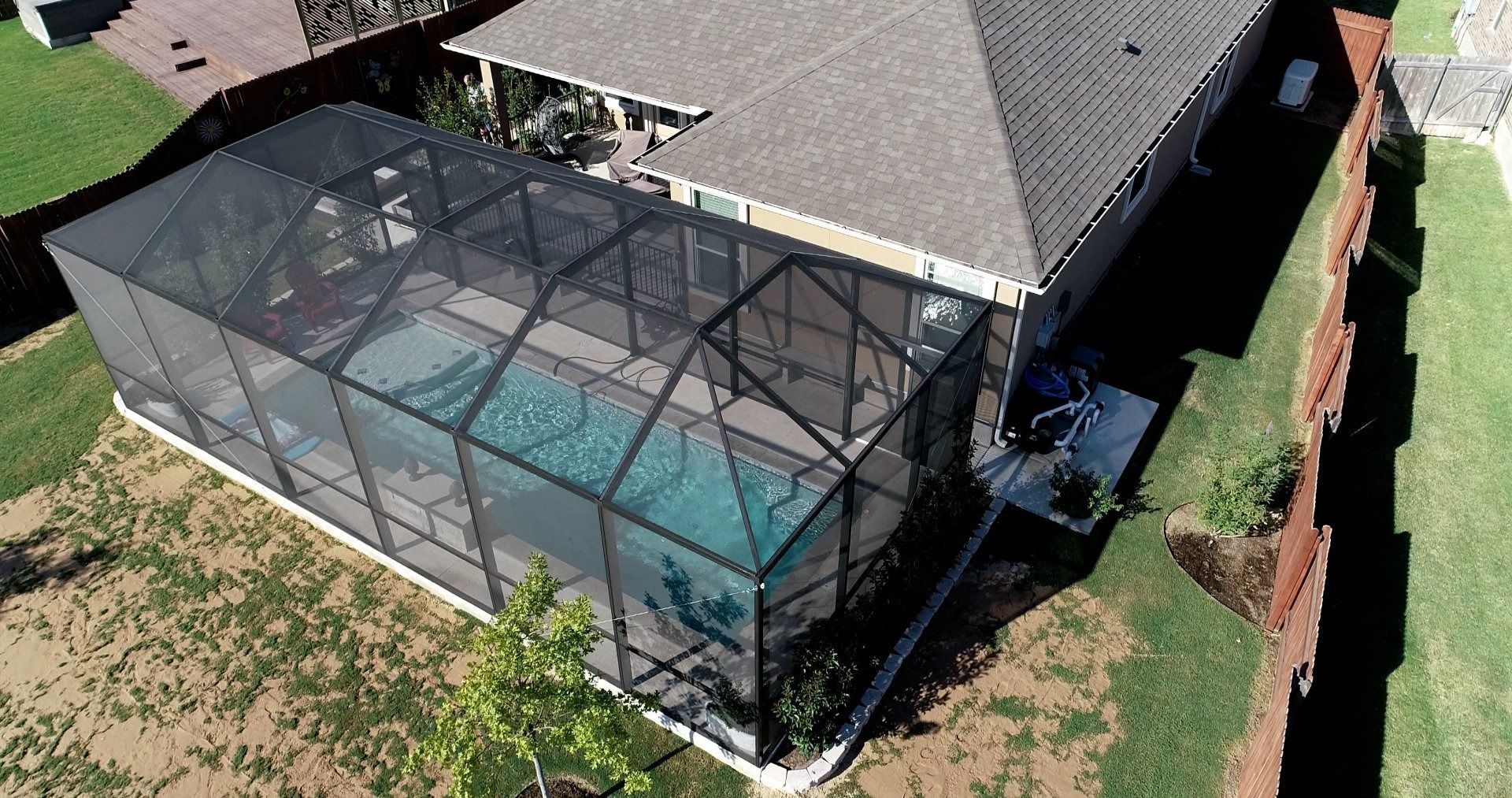 An aerial view of a house with a screened in swimming pool.
