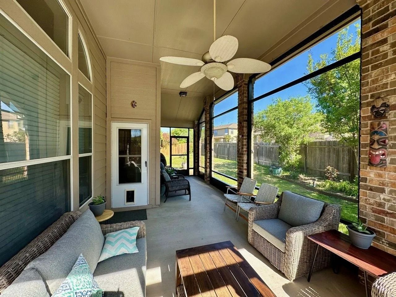 A screened in porch with furniture and a ceiling fan.