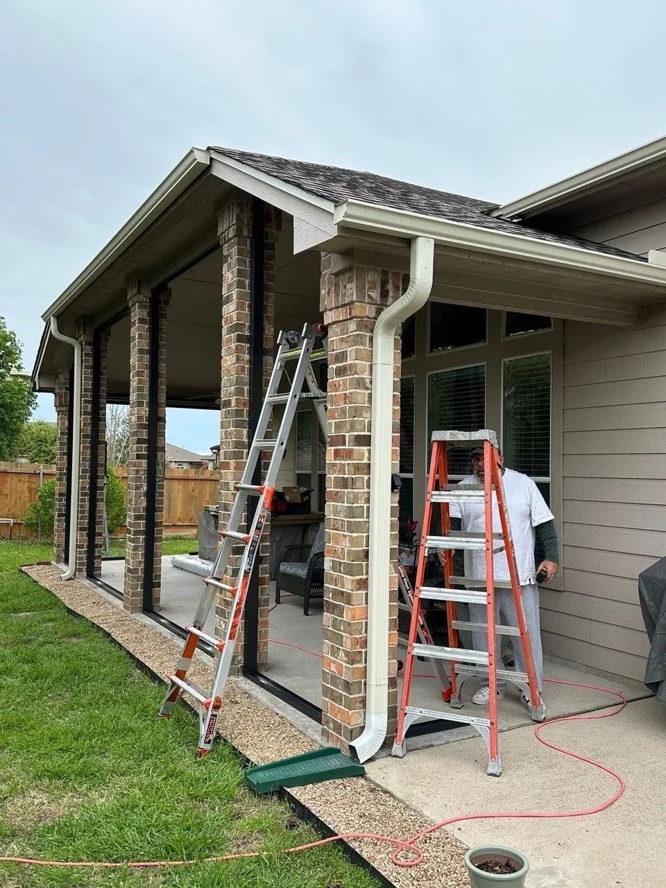 A man is standing on a ladder on the side of a house.