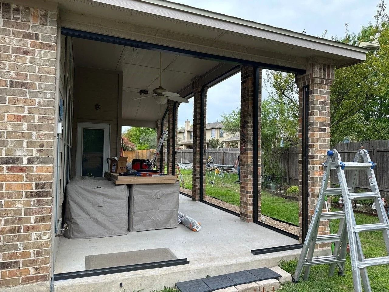 A sliding glass door is being installed on a brick house.