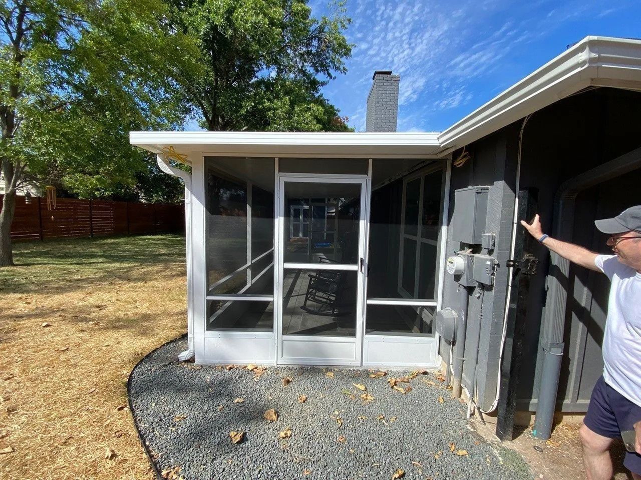 A man is standing in front of a screened in porch.