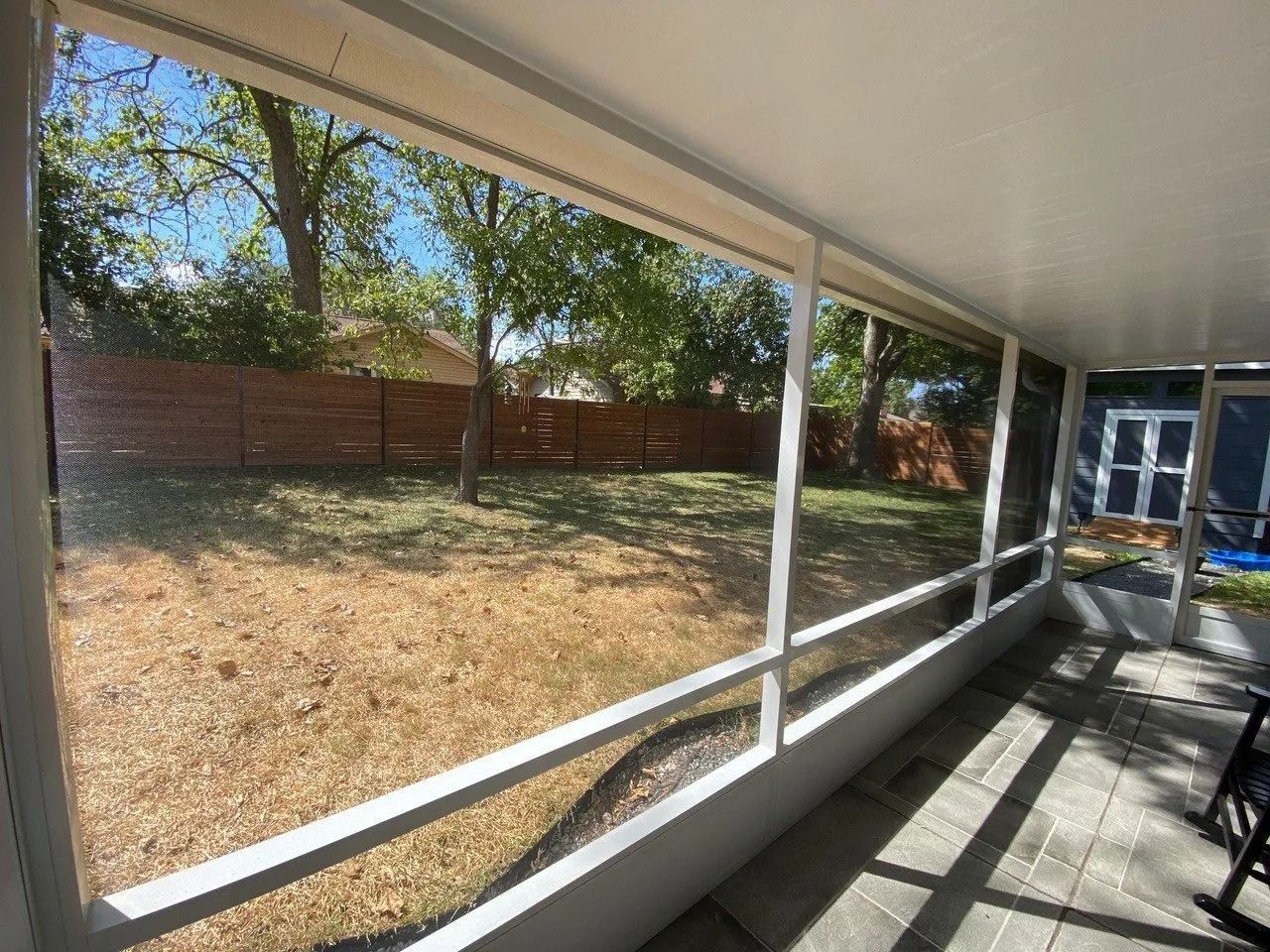 A screened in porch with a view of a backyard.