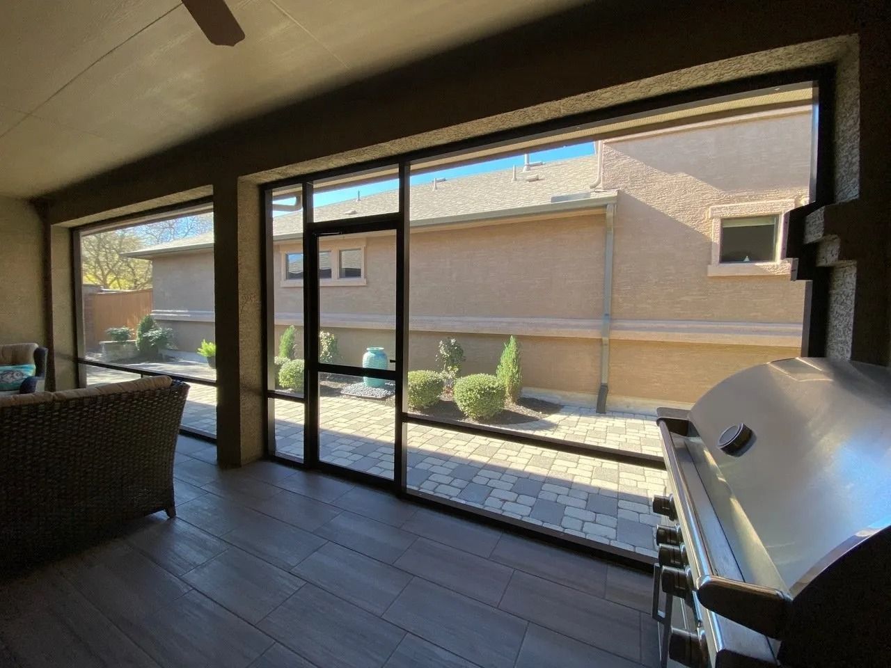 A screened in porch with a grill and a view of a house.