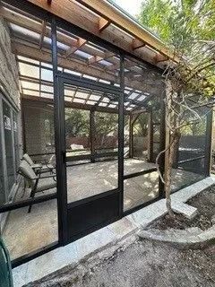 A screened in porch with a roof and a lot of windows.
