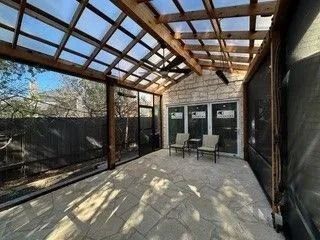 A screened in porch with a ceiling fan and chairs.