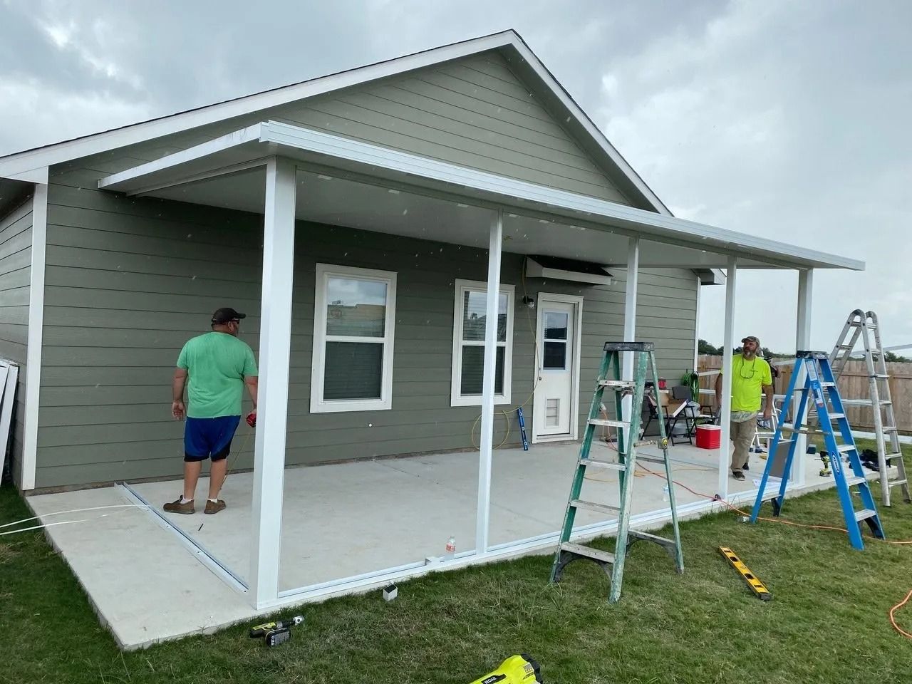 A man is standing on a porch in front of a house.