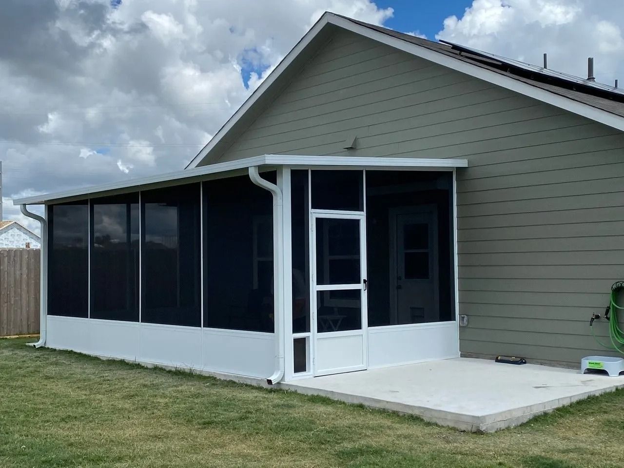 A screened in porch is attached to the side of a house.