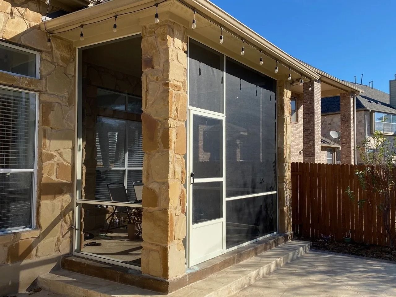 A screened in porch with a wooden fence in the background