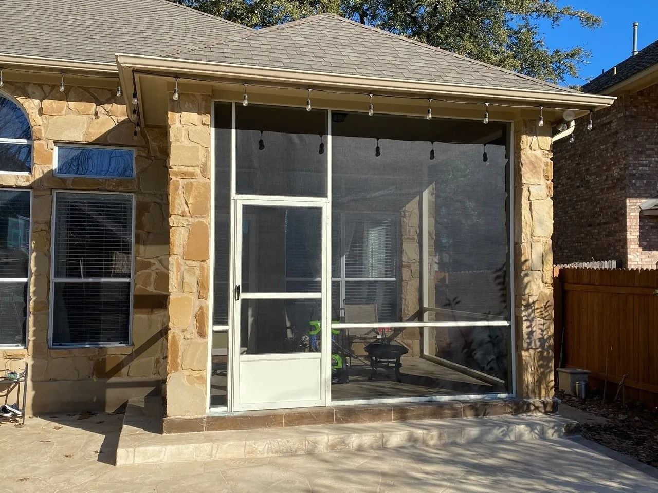 A house with a screened in porch and a fence in the backyard.