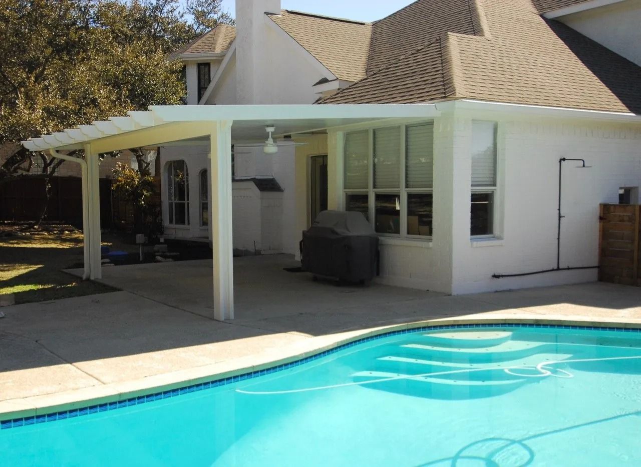 A house with a covered patio and a pool in front of it