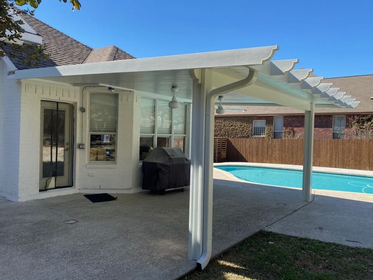 A white house with a covered patio next to a pool.