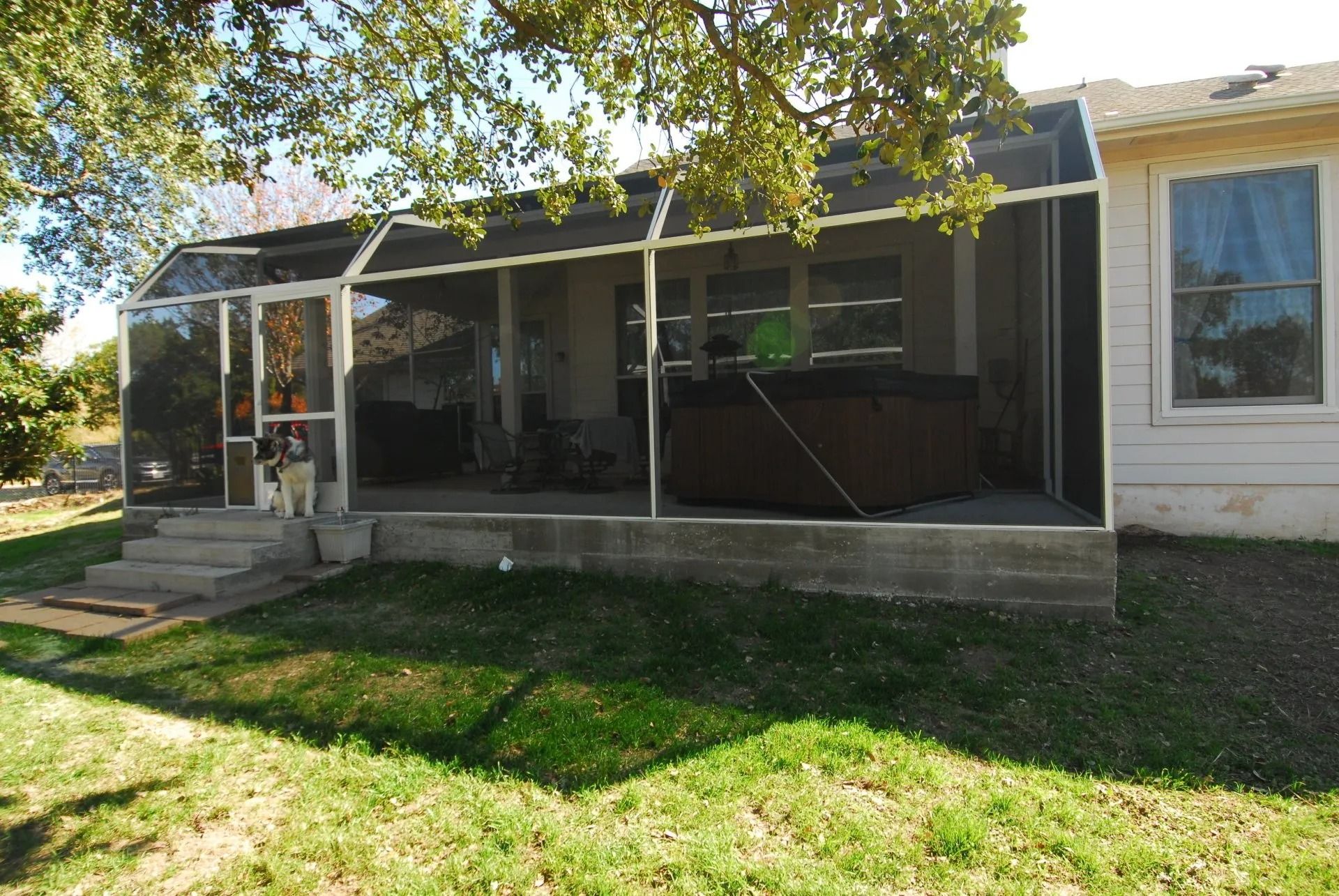 A house with a screened in porch and a hot tub