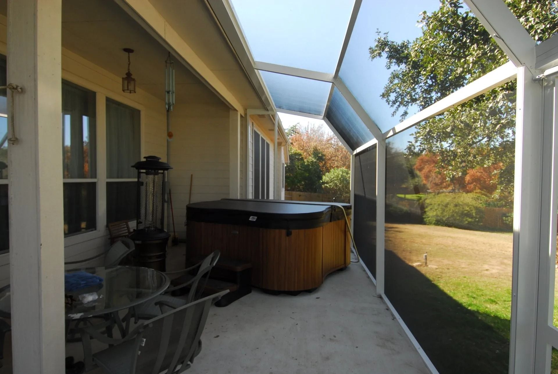 A screened in porch with a hot tub and a table