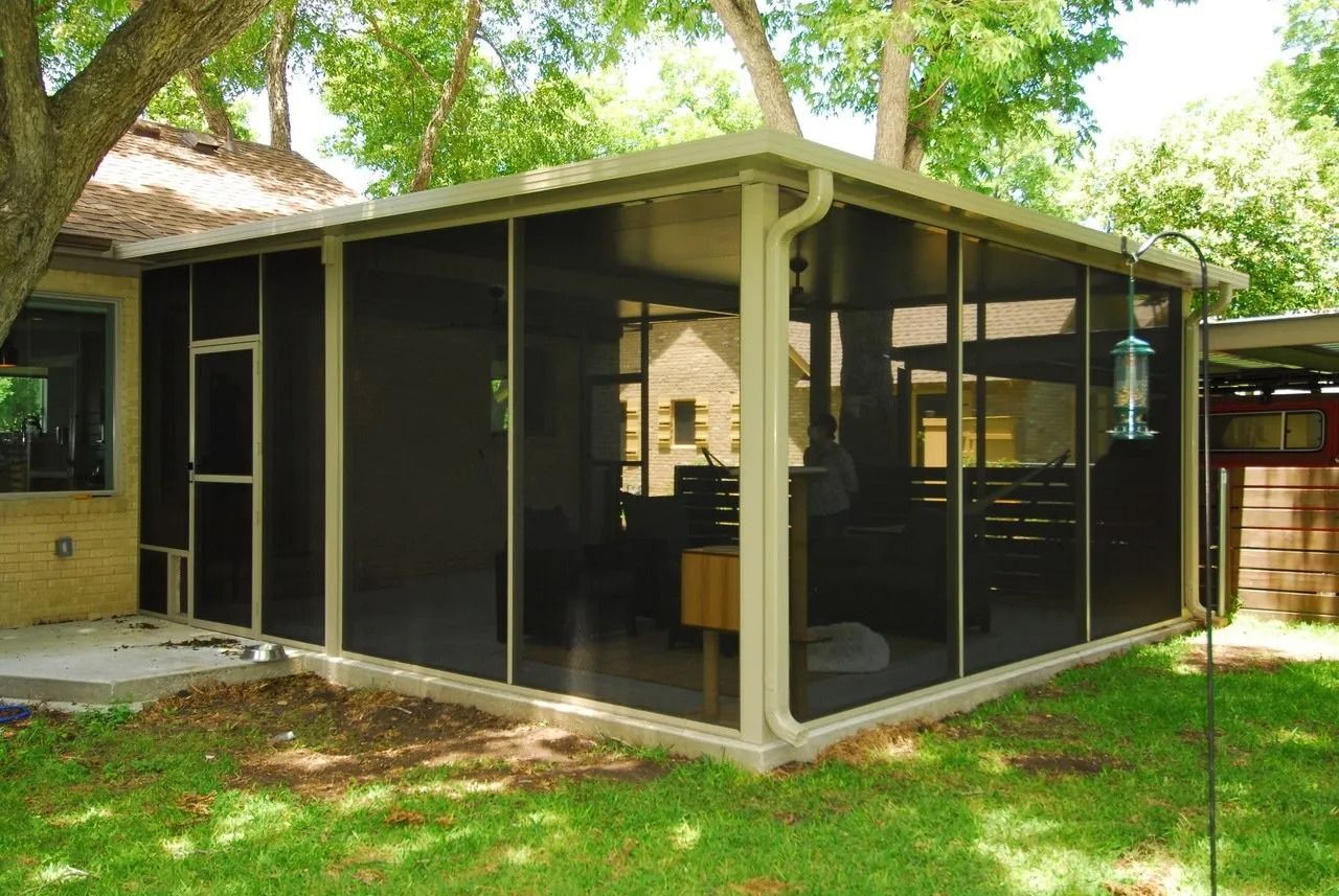 A screened in porch in the backyard of a house