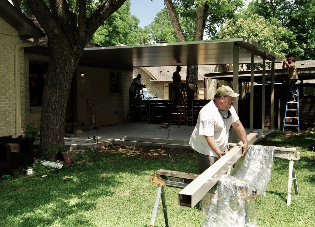 A man is holding a piece of wood in front of a house