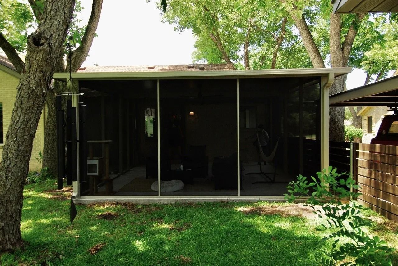 A screened in porch in the backyard of a house
