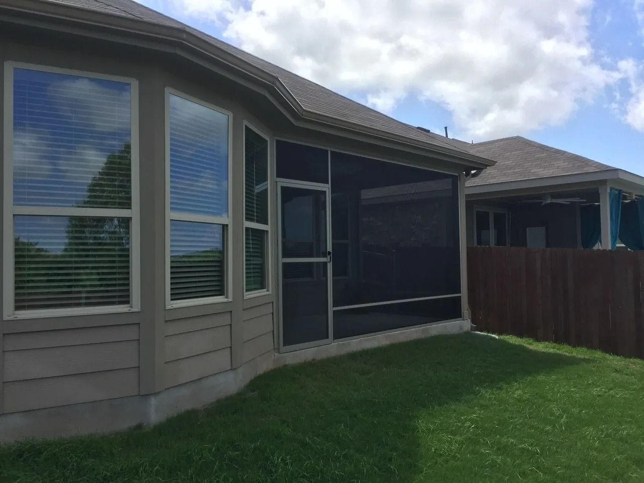 A house with a screened in porch and a fence in the backyard.