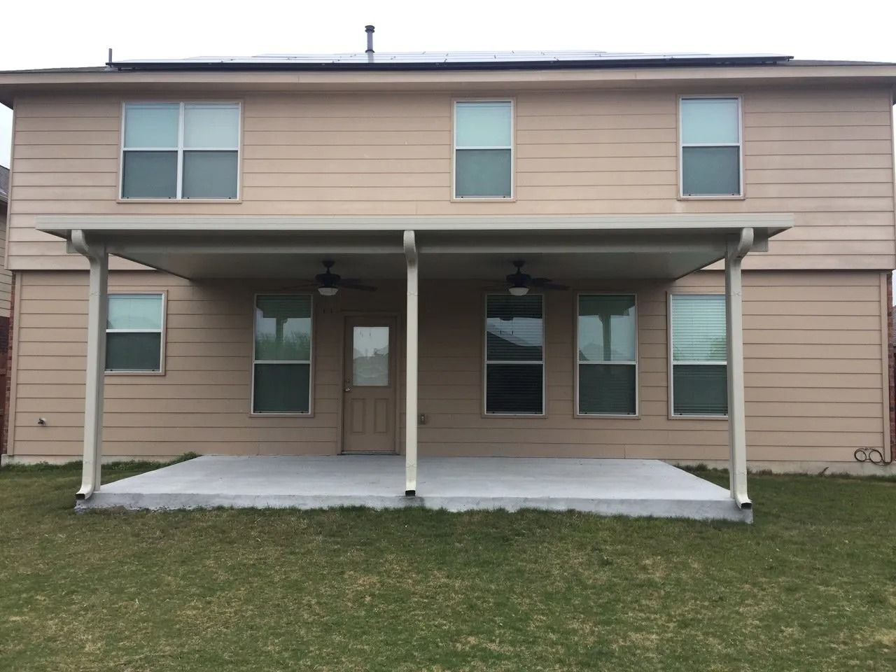 The back of a house with a porch and a lot of windows