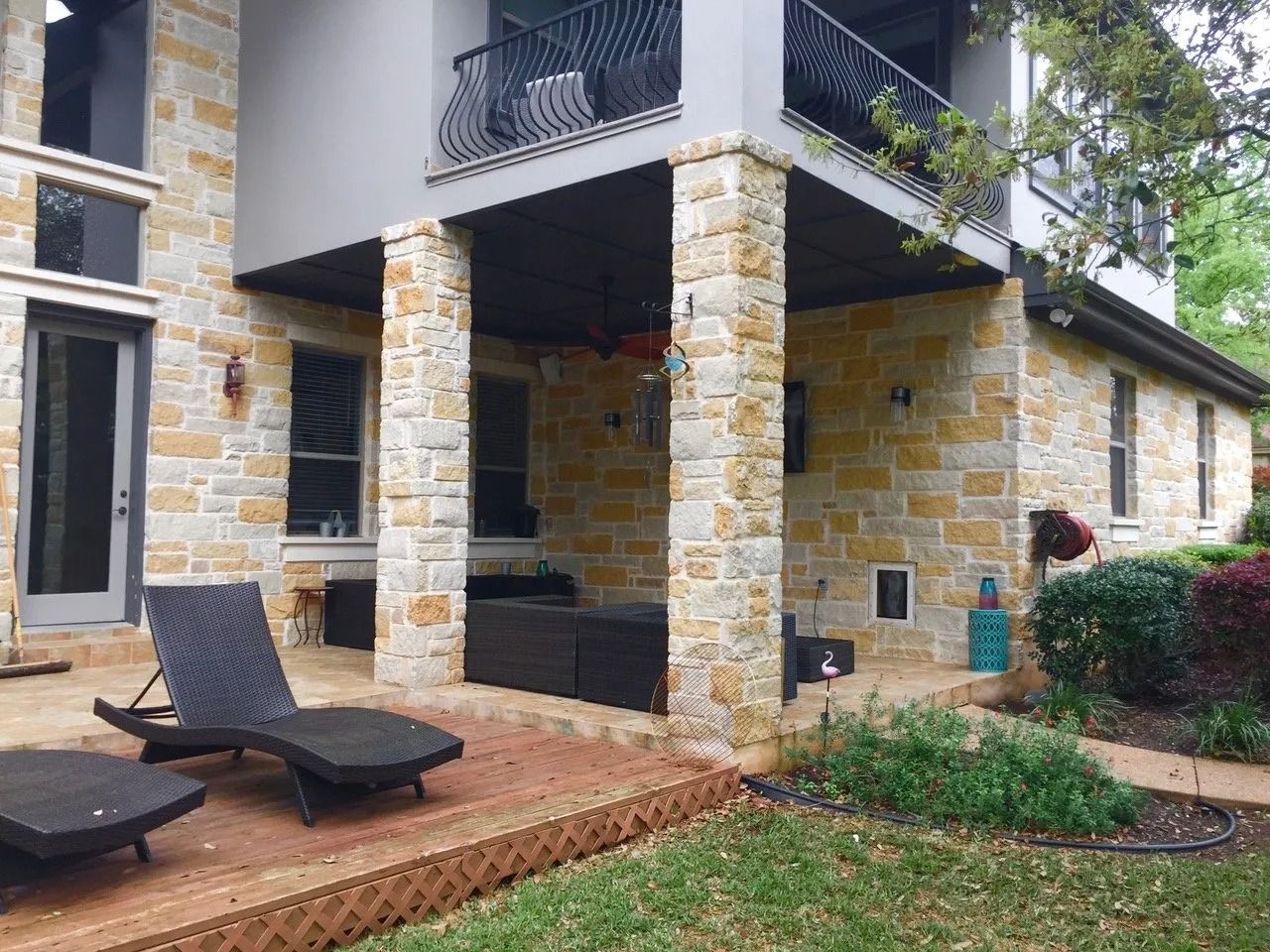 A large stone house with a patio and chairs in front of it.