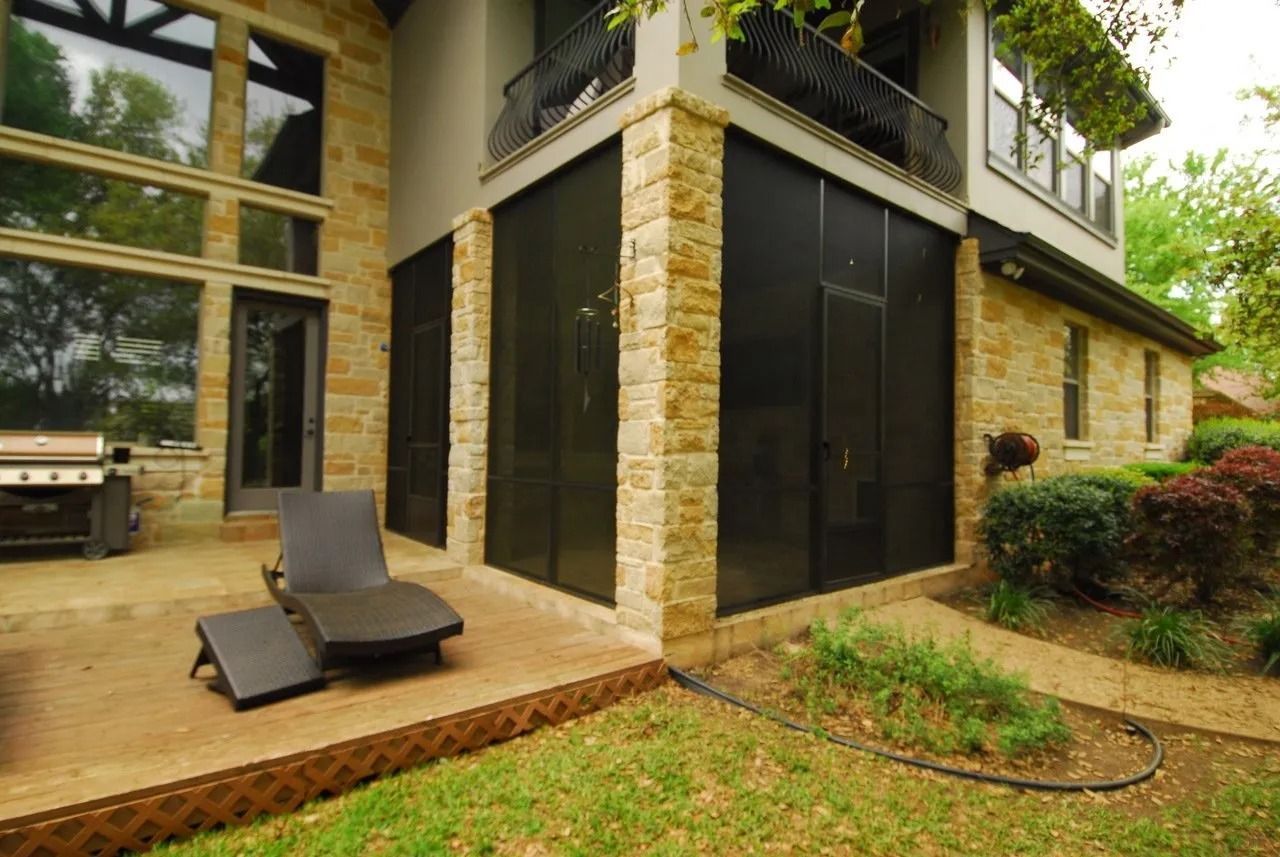 A large house with a screened in porch and a grill.