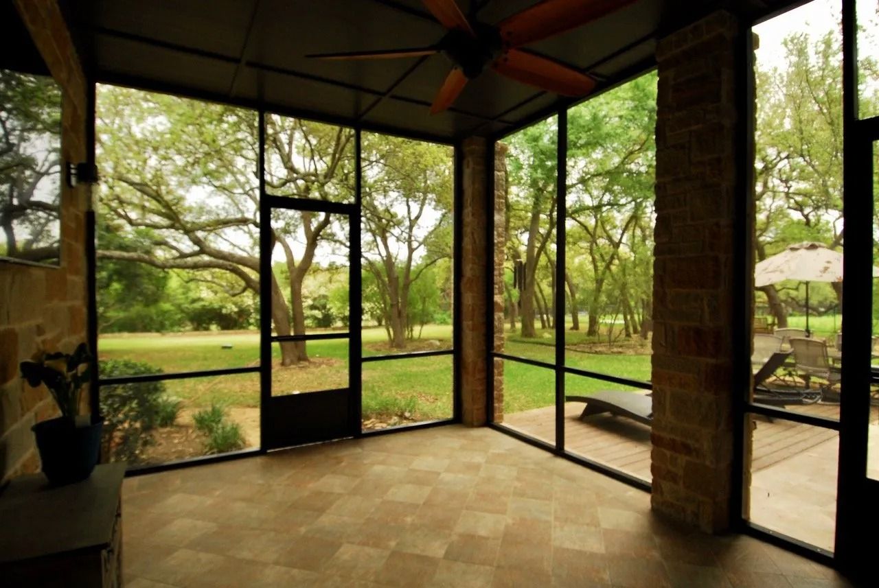 A screened in porch with a lot of windows and a ceiling fan.