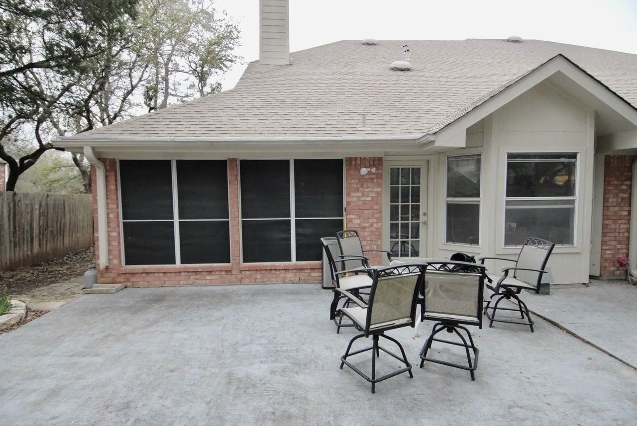 A screened in patio with a table and chairs in front of a house