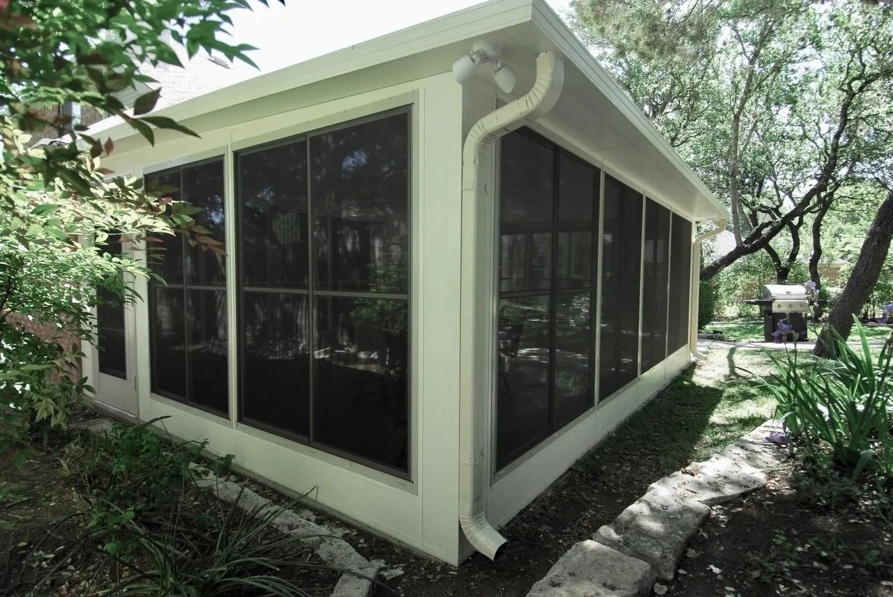 A screened in porch in the backyard of a house