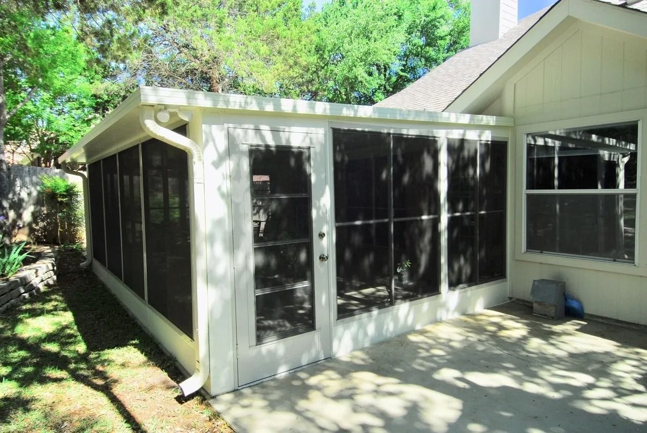A screened in porch in the backyard of a house