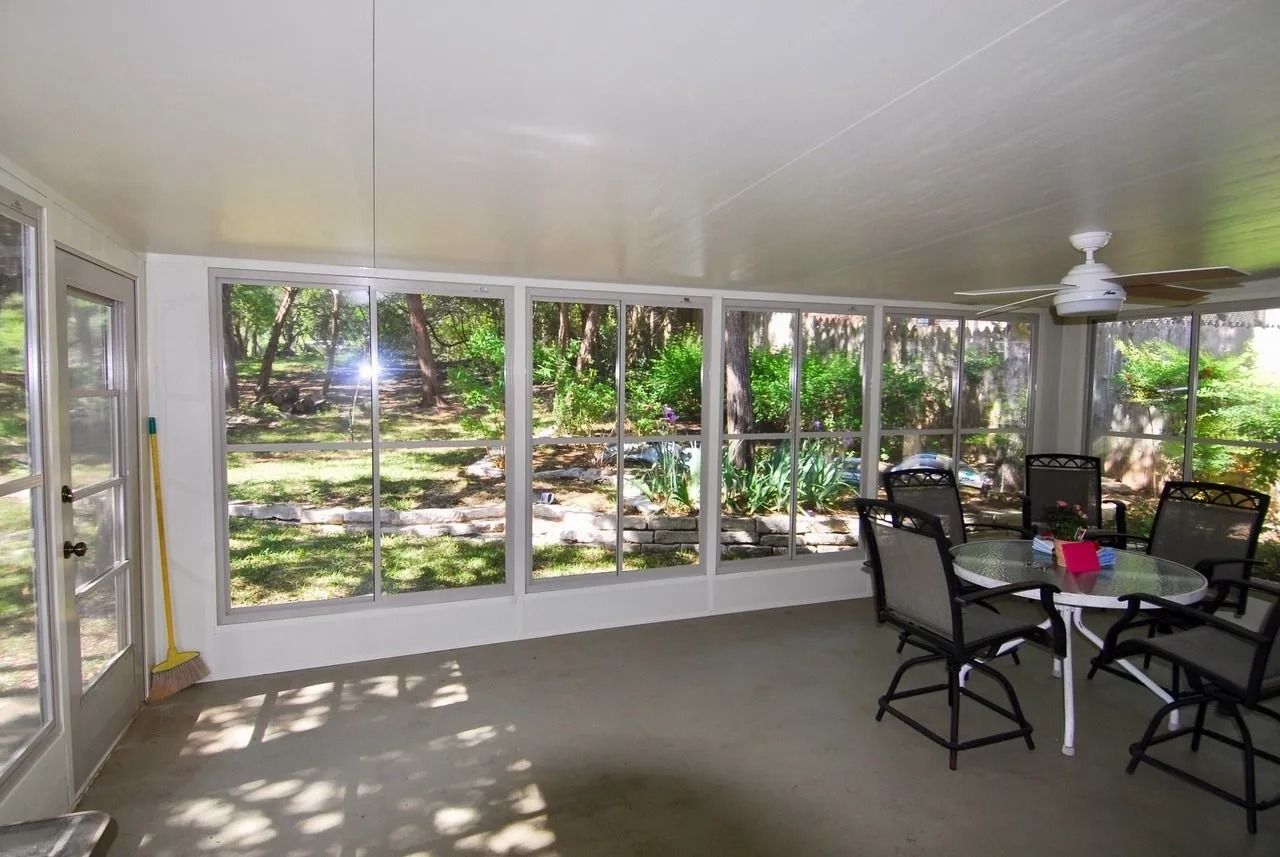 A screened in porch with a table and chairs