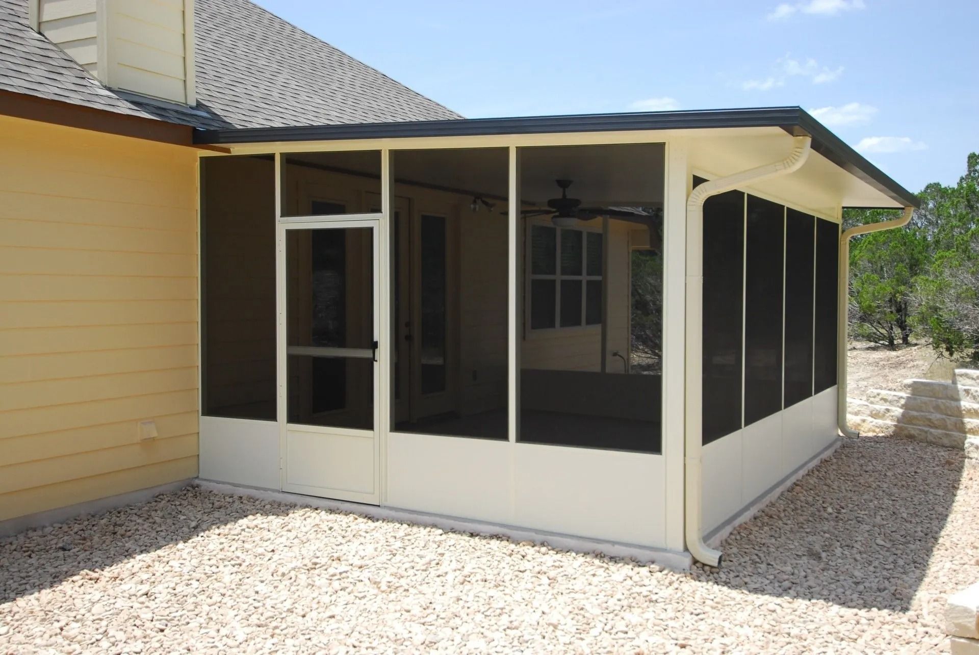 A screened in porch in the backyard of a house