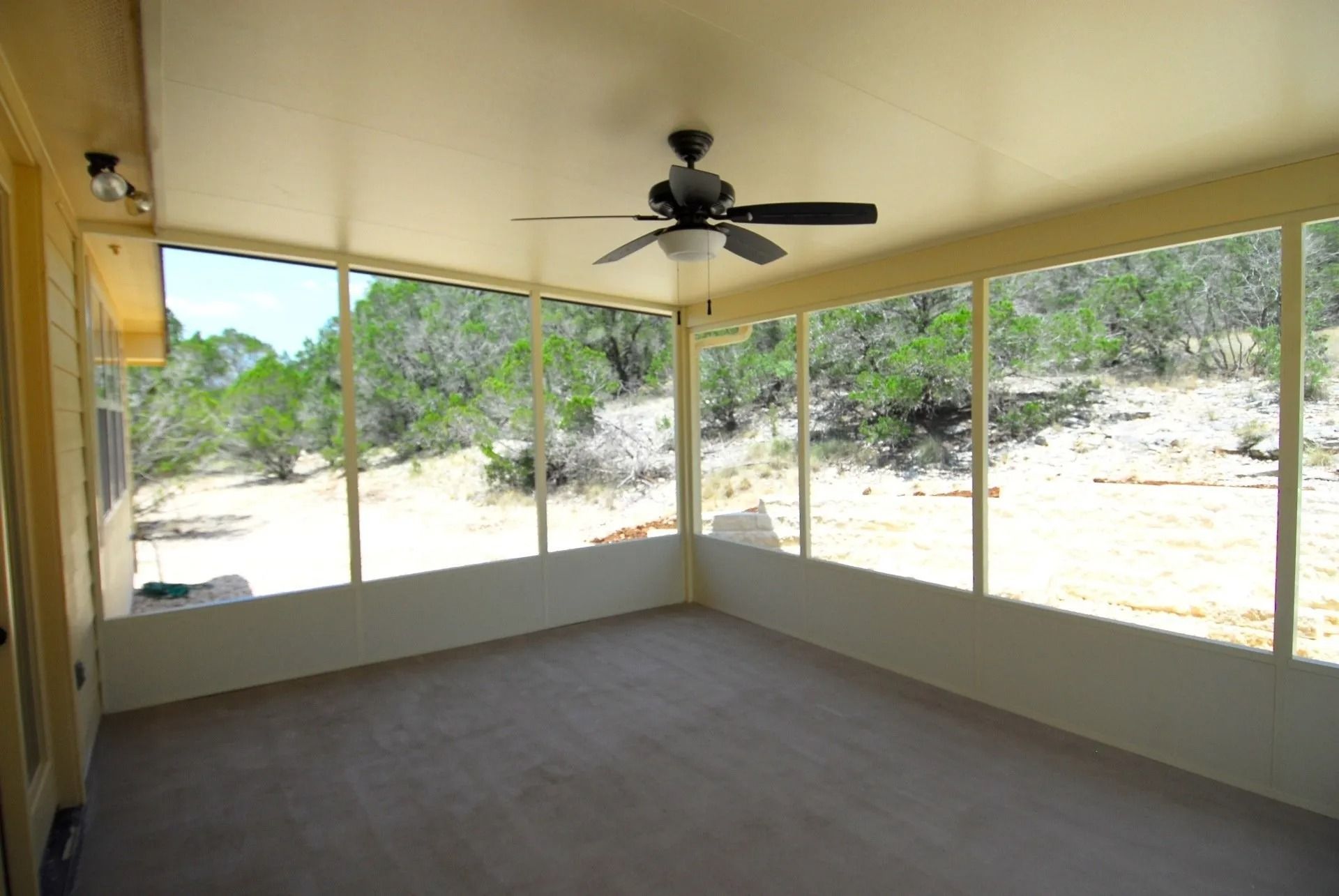 A screened in porch with a ceiling fan and lots of windows
