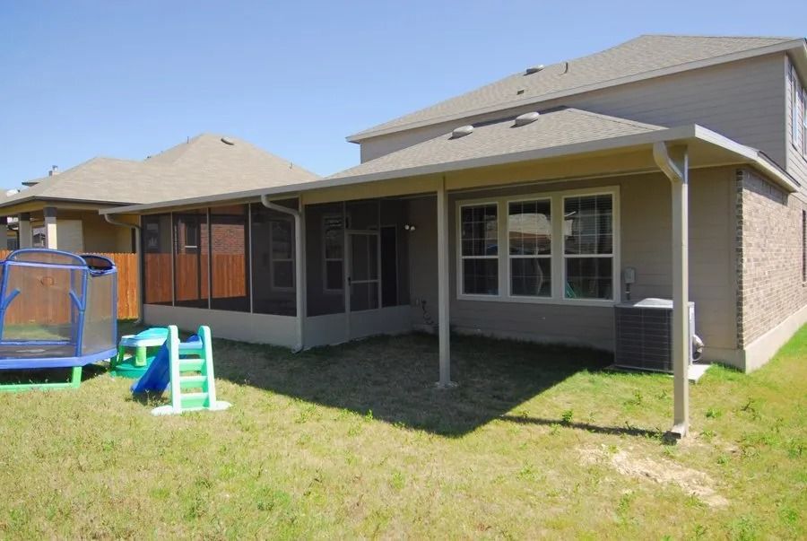 A house with a screened in porch and a trampoline in the backyard.