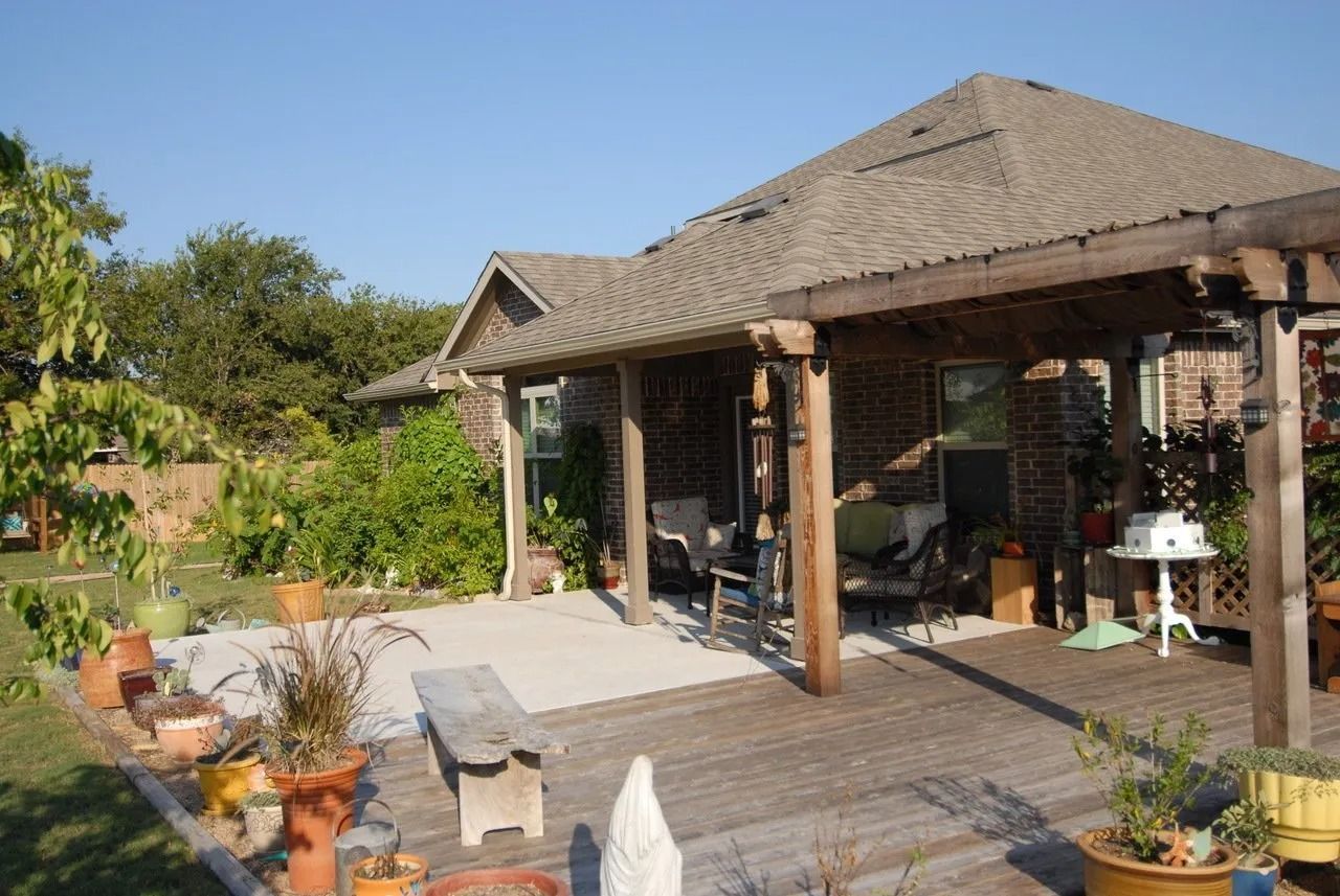 A house with a covered patio and lots of potted plants