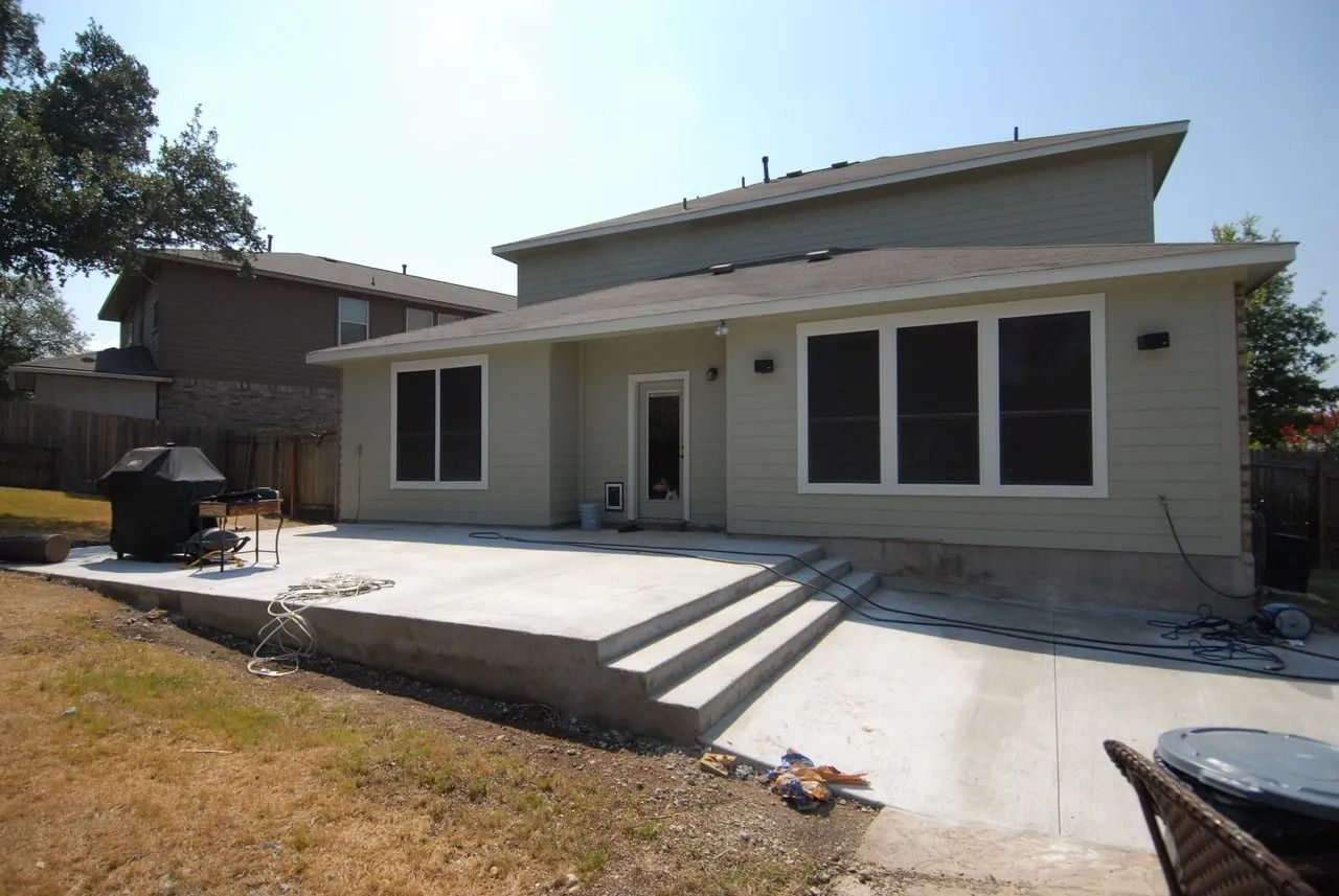 The back of a house with a patio in front of it.