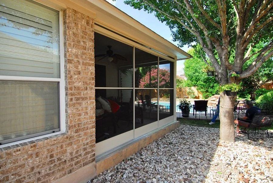 A brick house with a screened in porch and a tree