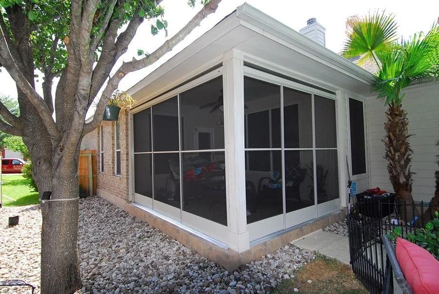 A screened in porch with a tree in the background