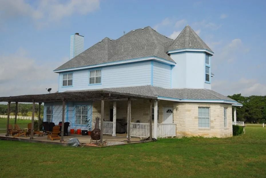 A blue house with a gray roof and a porch
