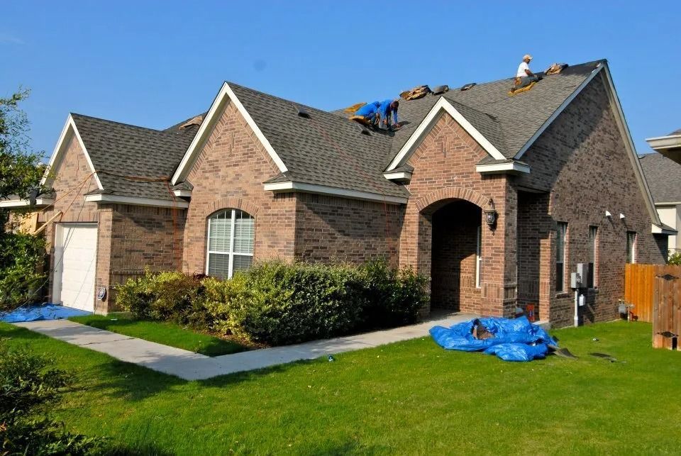 A man is working on the roof of a brick house.