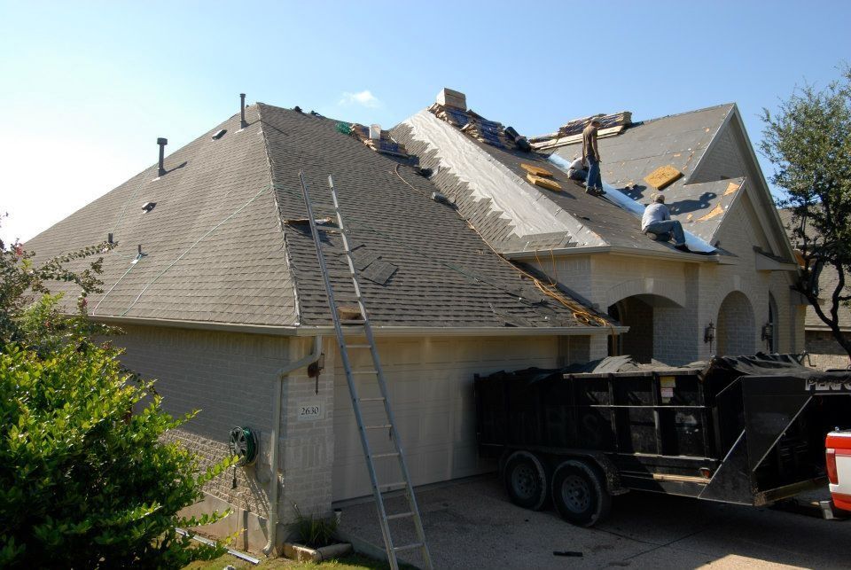A house with a ladder and a dumpster in front of it