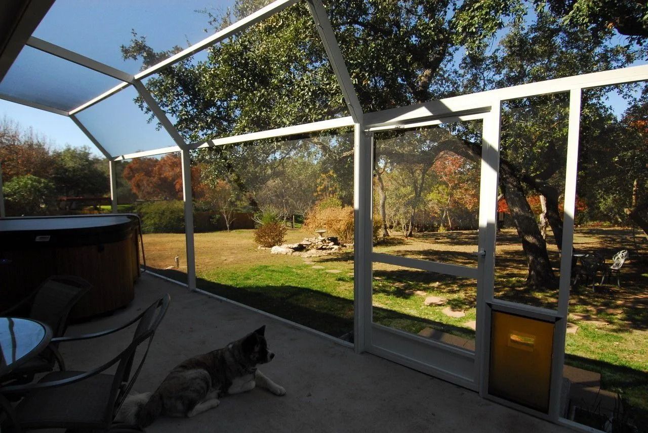 A screened in porch with a hot tub in the background