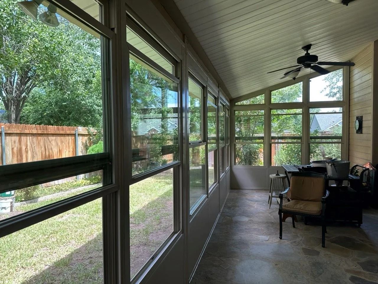 A sunroom with a lot of windows and a ceiling fan.